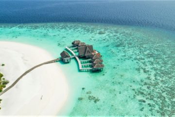 Droneshot van strand met resort hutjes in de Malediven