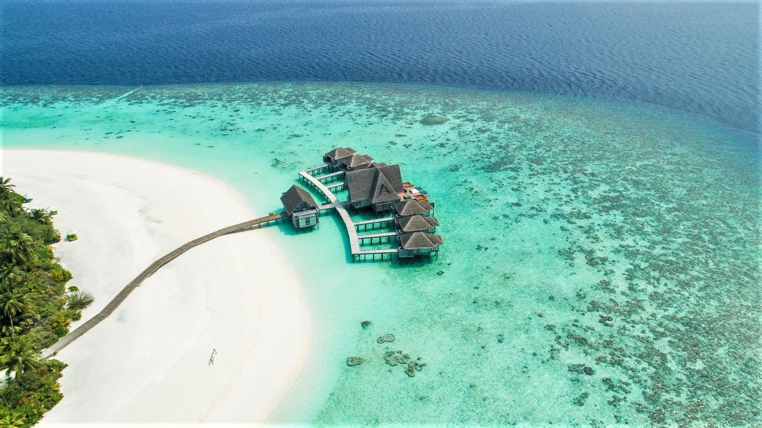 Droneshot van strand met resort hutjes in de Malediven
