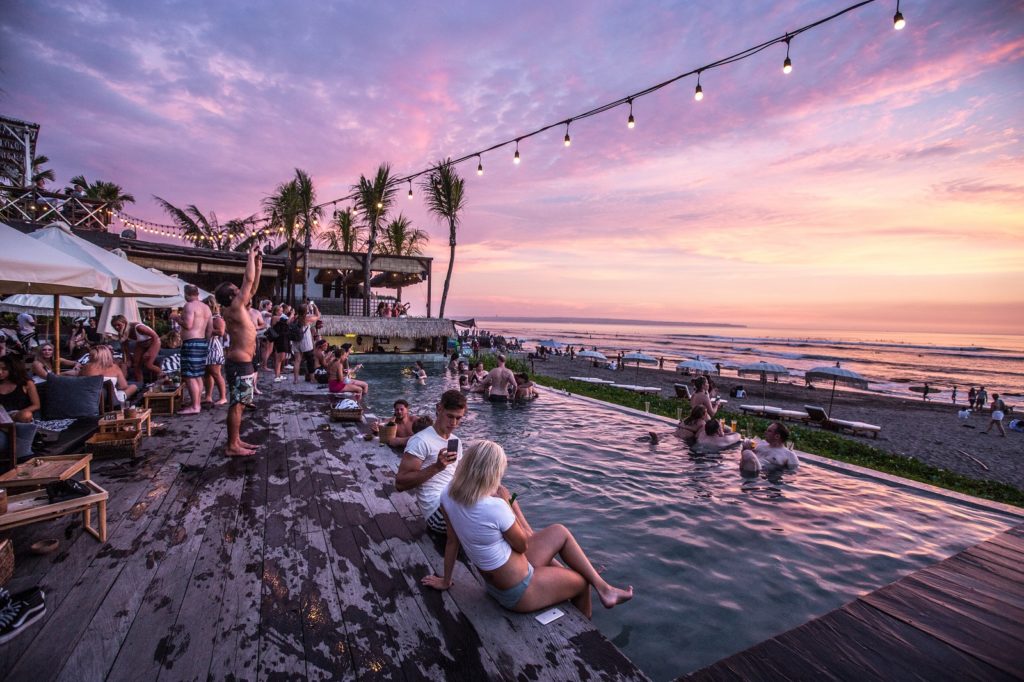 Mensen chillen bij het zwembad en strand bij Canggu The Lawn bij leuke plaatsen Bali