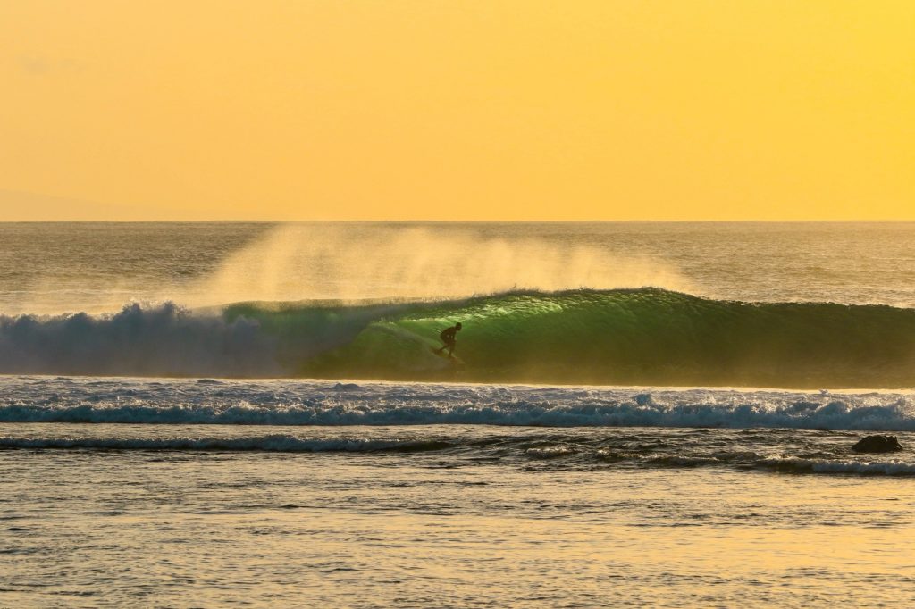 Surfer surft op zee op een van de mooiste plekken van Lombok